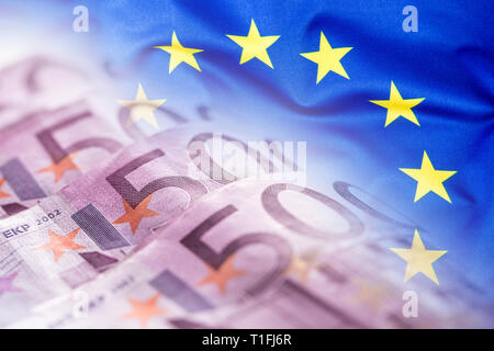 Bunte wehende Fahne der Europäischen Union auf einen Euro Geld Hintergrund Stockfoto