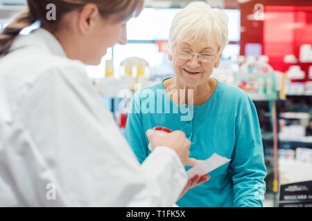 Ältere Frau in der Apotheke das Gespräch mit dem Chemiker oder Apotheker Stockfoto