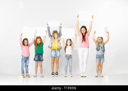 Gruppe von wütenden Kinder mit einem weißen leeren Banner in Light Studio Hintergrund isoliert. Bildung und Werbung Konzept. Protest und Rechte der Kinder Konzepte. Stockfoto