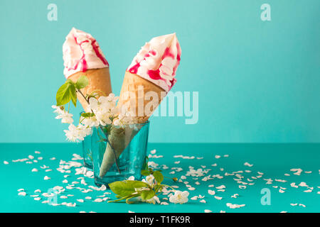 Schmelzende Eis mit Früchten Sirup eingerichtet weiß Cherry Blossom auf blauem Hintergrund Stockfoto