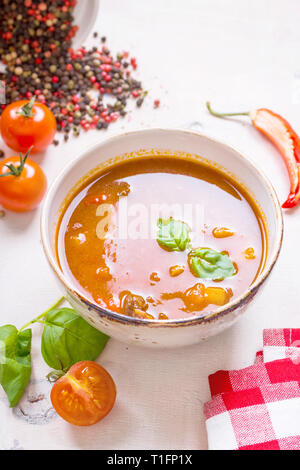 Tomatensuppe mit Fleisch in einer weißen Schüssel auf weißem Holz- Hintergrund Stockfoto