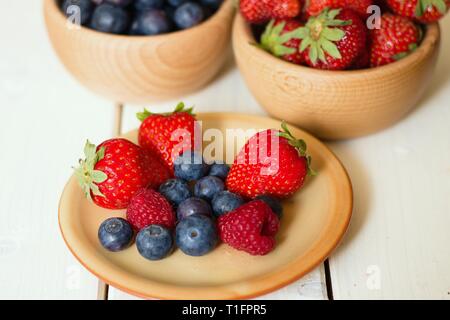 Erdbeeren, Himbeeren und Heidelbeeren, oder den Wald Obst auf einem Schild vor der hölzernen Schüsseln Stockfoto