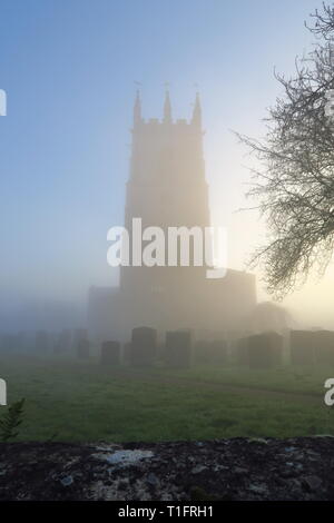 Am frühen Morgen Nebel im Norden Oxfordshire Dorf Hook Norton mit der Pfarrkirche St. Peter emerging Stockfoto