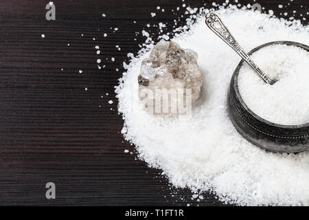 Alte silberne Salzstreuer mit Löffel, rohe natürliche Halit Mineral- und feinkörnigen Steinsalz schließen bis auf Dunkelbraun Holzbrett Stockfoto