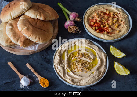 Platten von Hummus mit Fladenbrot auf schwarzem Hintergrund Stockfoto