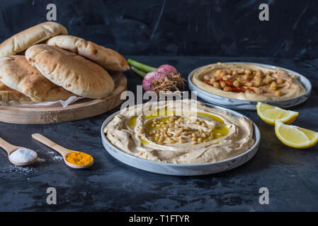 Platten von Hummus mit Fladenbrot auf schwarzem Hintergrund Stockfoto