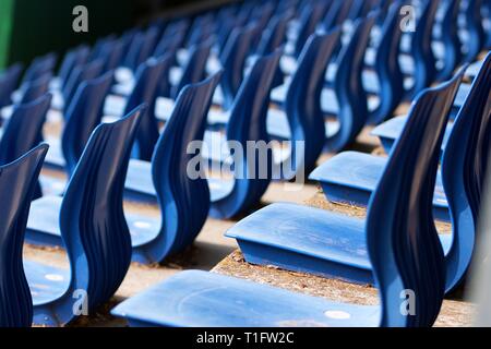 Sitze der lokalen Outdoor Sport oder kulturellen Veranstaltungsort an einem sonnigen Tag. Reihen von Blau strapazierfähiger Kunststoff Sitze ohne Menschen erschossen leicht von zurück Stockfoto