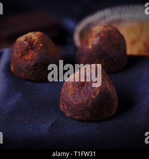 Mehrere Stücke Schokolade Trüffel mit Kakaopulver auf dunklem Hintergrund. Konzept der Qualität süßes Essen, Luxus, Schokolade Stockfoto
