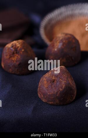 Schokolade Trüffel mit Kakaopulver auf dunklem Hintergrund. Mehrere Stücke von uxury Süßigkeit auf dem Löffel. Konzept der Qualität süßes Essen, Luxus, choco Stockfoto