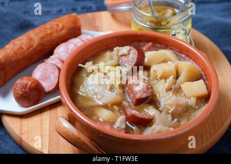 Kohlsuppe mit Kartoffeln und Wurst im Tontopf Stockfoto