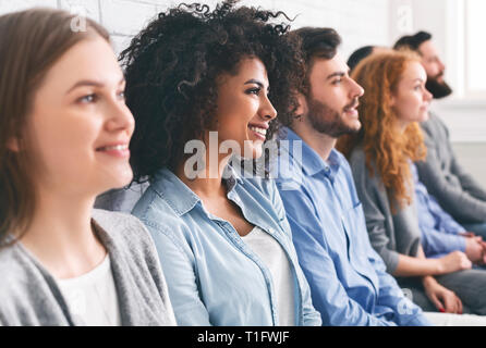 Diverse tausendjährigen Gruppe in der Reihe Sitzen, Warten auf etwas Stockfoto