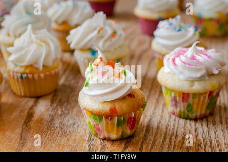 Verschiedene mini Muffins im Frühjahr und Ostern Farben dekoriert. Hintergrund einer rauhen Holz Tisch. Stockfoto