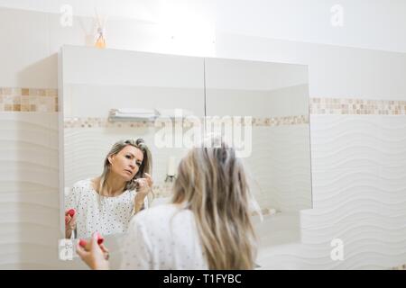 Frau Anwendung Morgens im Badezimmer Spiegel machen, Behandlung zu Hause. Stockfoto