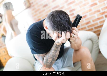Unglückliche Menschen fernsehen und Frau im Hintergrund. Der Mann und die Frau zu Hause. Stockfoto