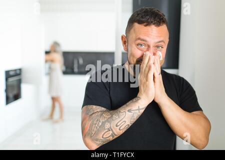 Mann in der Küche in Heuschnupfen mit Seidenpapier zu löschen Nase. Stockfoto