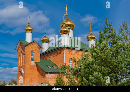 Red Brick christliche Kirche mit goldenen Kuppeln vor blauem Himmel Stockfoto