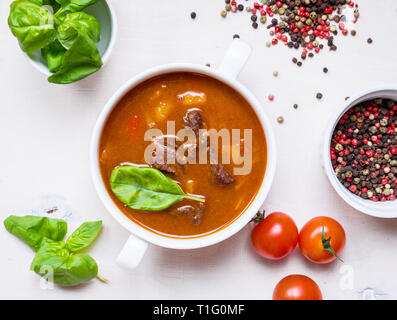Tomatensuppe mit Fleisch in einer weißen Schüssel auf weißem Holz- Hintergrund Stockfoto