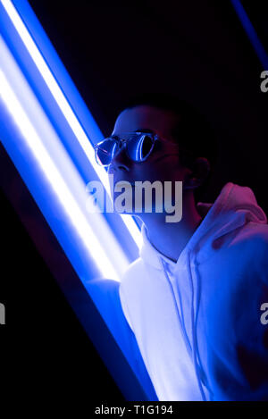 Bunte Porträt einer jungen Frau mit kurzen Haaren glänzende Sonnenbrille und Stellung im Neonlicht. Stockfoto