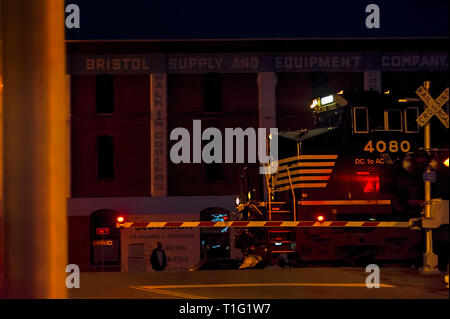 Bristol, Virginia/Tennessee, USA - März 20,2019: ein Zug Motor Fortschritte auf der State Street Bahnübergang in der Nacht in Bristol. Stockfoto