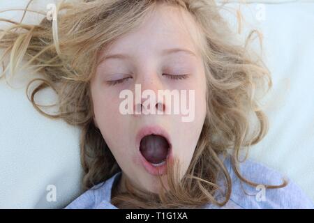 Mädchen mit blonden Locken Gähnen und Aufwachen mit geschlossenen Augen Stockfoto