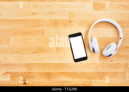 Mit leeren weißen Bildschirm und drahtlose Kopfhörer für Holz- büro Schreibtisch Smartphone. Ansicht von oben. Kopieren Sie Platz für Text oder Design. Flach. Stockfoto