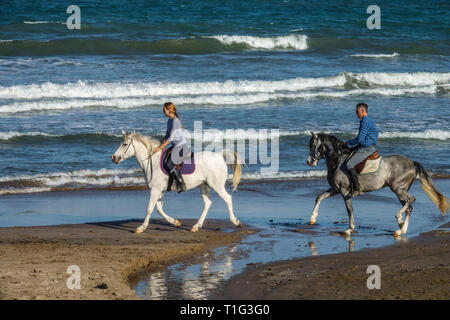 Paar Reiten am Strand Stockfoto