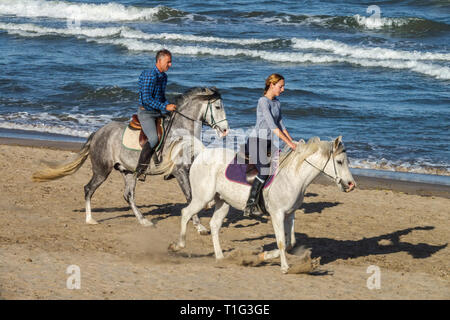 Paar Reiten am Strand Stockfoto