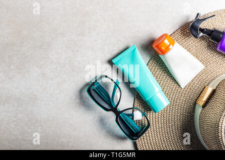 Sonnenschutzmittel auf grauem Hintergrund, flach. Frühling und Sommer Schutz vor der Sonne Stockfoto