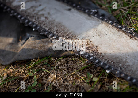 In der Nähe von verschmutzten Kettensäge Kette platziert auf dem Boden auf Gras. Stockfoto