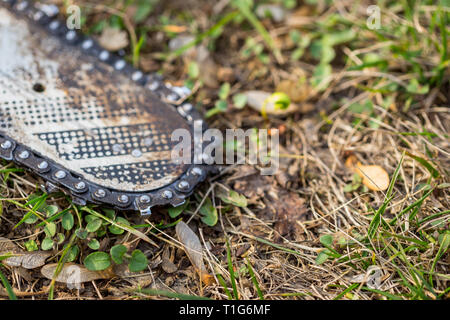 In der Nähe von verschmutzten Kettensäge Kette platziert auf dem Boden auf Gras. Stockfoto