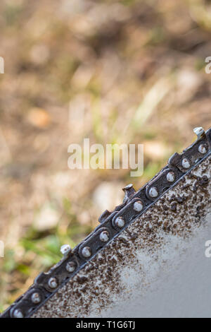 In der Nähe von verschmutzten Kettensäge Kette platziert auf dem Boden auf Gras. Stockfoto