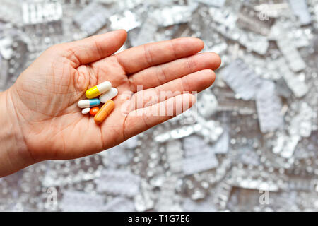 Hand mit vielen verschiedenen Tabletten vor leeren blister Pakete, multi-Medikation Konzept Stockfoto