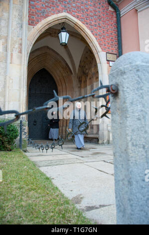 Eine Nonne verlassen die Kathedrale des Hl. Johannes des Täufers, am Cathedral Insel oder Ostrow Tumski, Breslau. Fokus auf Frau, Wandern, durch einen Zaun gesehen Stockfoto