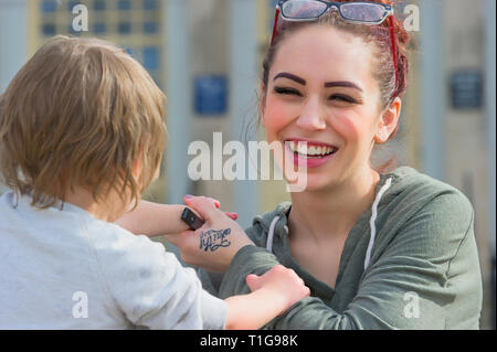 Glücklich lächelnde junge Mutter mit ihrem Kind spielen. Stockfoto