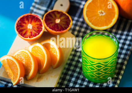 Orangensaft und Orangen auf blauem Hintergrund isoliert Stockfoto