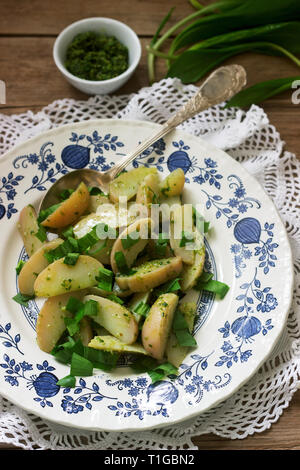 Vegetarischer Kartoffelsalat mit Bärlauch und Pesto auf einem hölzernen Hintergrund. Im rustikalen Stil. Stockfoto