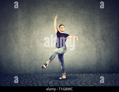 Stilvolle junger Mann in Jeans Kleidung tanzen mit auf grauen Hintergrund Stockfoto