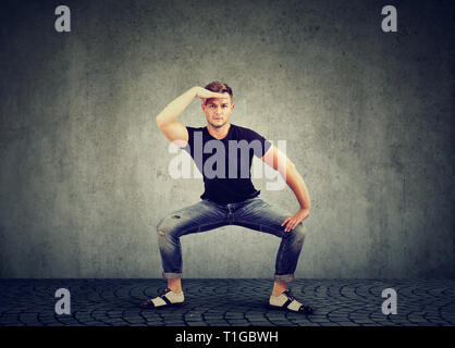 Stilvolle junger Mann in Jeans Kleidung tanzen mit auf grauen Hintergrund Stockfoto