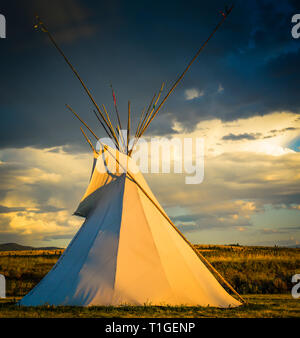 Ein Blick auf ein Tipi mit einem dramatischen Himmel in der Western Plains bei Sonnenuntergang in den USA Stockfoto