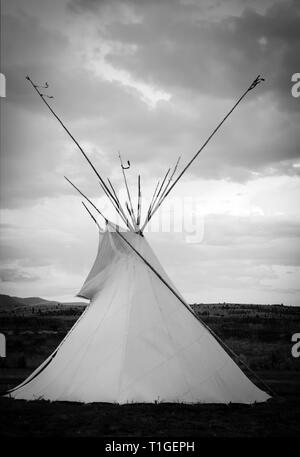 Blick auf ein Tipi in Schwarz und Weiß mit dramatischer Himmel in der Western Plains bei Sonnenuntergang in den USA Stockfoto