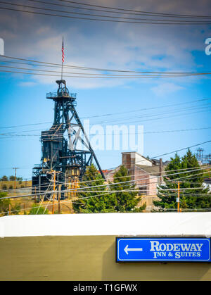 Ein Zeichen für das Rodeway Inn & Suites Hotel vor einem alten veraltet mein Haupt Frame über eine alte Mine Welle in der Minenstadt Butte, MT, USA Stockfoto