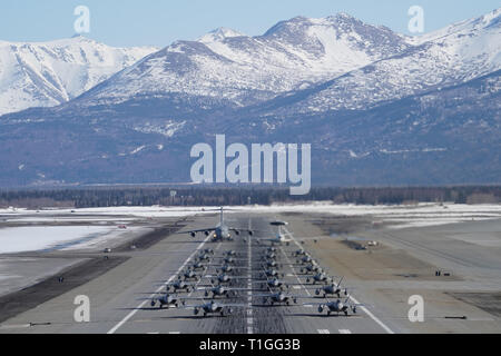 F-22 Raptors aus der 3 Flügel und 477th Fighter Group beteiligen sich in einer engen Formation Taxi mit einem E-3 Sentry und eine C-17 Globemaster III, bekannt als ein Elephant Walk, 26. März 2019, während eines Polar Kraft Übung in Joint Base Elmendorf-Richardson, Alaska. Dieser zweiwöchige Übung gibt staffeln die Möglichkeit, ihre Fähigkeiten unter Beweis zu stellen, Bereitstellen und liefern überwältigende bekämpfen Airpower. (U.S. Air Force Foto von Justin Connaher) Stockfoto