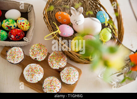 Ostern, close-up Tisch mit glasierte Cupcakes, Korb mit Ostereiern und Bunny. Happy Family Urlaub. top View Stockfoto