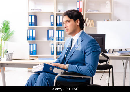 Männliche Angestellte im Rollstuhl im Büro arbeiten Stockfoto