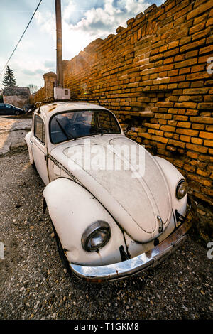 Zemun, Serbien - 17. Februar 2019 - alten verrosteten weißen Volkswagen Käfer neben orange Wand geparkt. Stockfoto