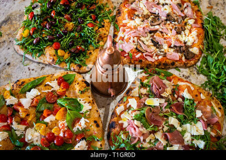 Eine Auswahl an authentischen Römisch-italienischen Stil Holzofen Pizzas, auf einem Marmor Zähler, in einer Trattoria Pizzeria Restaurant Stockfoto