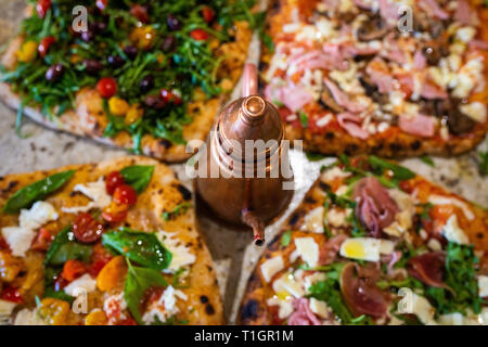 Eine Auswahl an authentischen Römisch-italienischen Stil Holzofen Pizzas auf einem Marmor Zähler, in einer Trattoria Pizzeria Restaurant Stockfoto