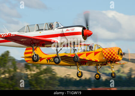 Zwei Jakowlew Jak-52 Flugzeuge nehmen Sie am Flügel über Wairarapa Airshow an Haube Flugplatz, Masterton, Neuseeland. ZK-KGB- und ZK-YNZ Ebene Stockfoto