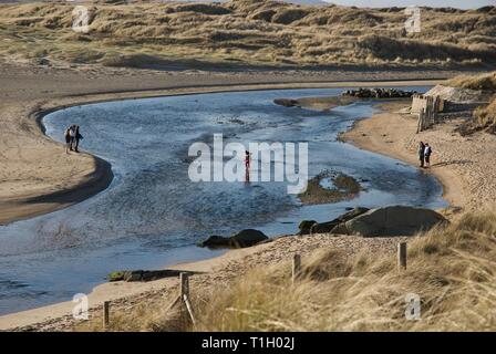 Ferner Zahlen über die Afon Crigyll Fluss waten, Rhosneigr, Anglesey, North Wales, UK Stockfoto