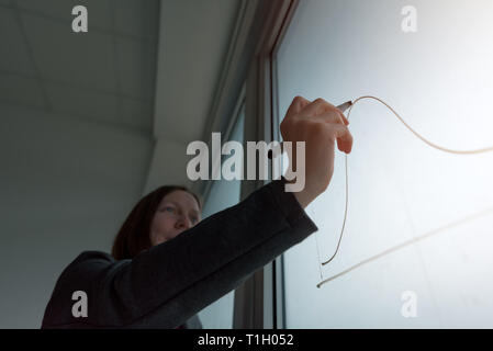 Geschäftsfrau Zeichnung Grafik auf dem Whiteboard im Büro während der Präsentation der Ergebnisse beim Corporate Meeting Stockfoto